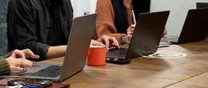 Ein Team sitzt am Tisch am Laptop und arbeitet
